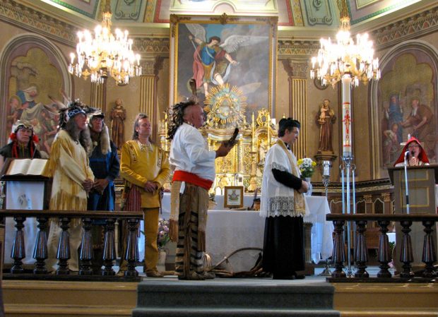 Photographie couleur, intérieur d’une église richement décorée, célébration religieuse dont les participants sont en costumes d’époque. 
