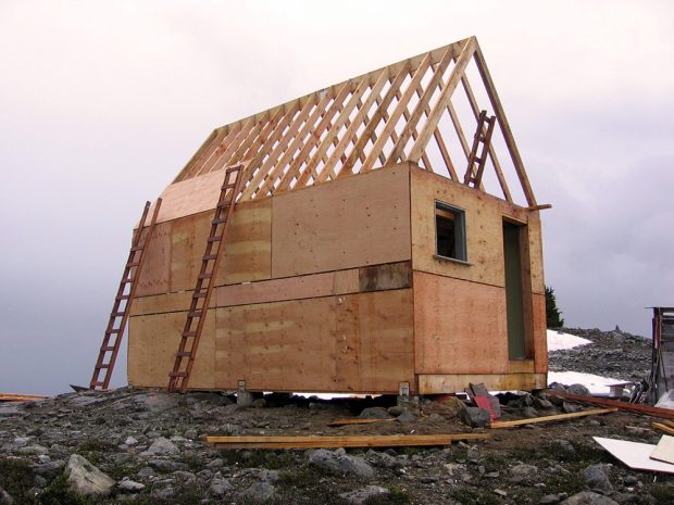 La charpente en bois du refuge a été construite et les murs extérieurs sont recouverts de contreplaqué. Le toit reste exposé aux intempéries et deux échelles en bois sont installées à l’extérieur.