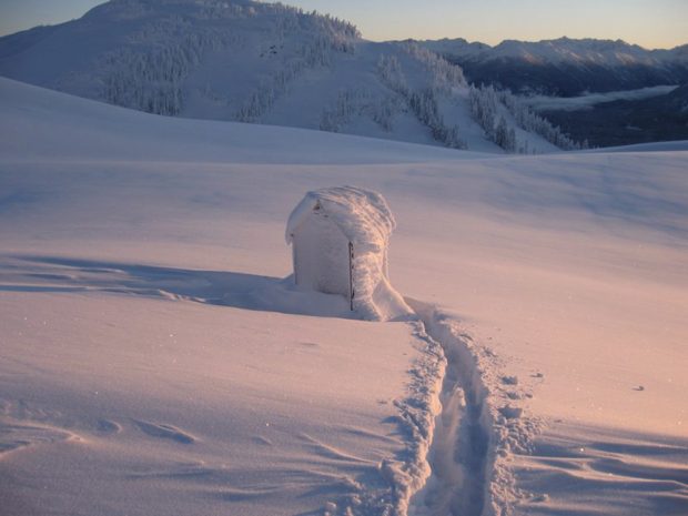 Piste déblayée menant à l’entrée de toilettes extérieures isolées.