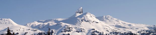 Le sommet volcanique noir de l’Aiguille noire blanchi de neige se dresse au-dessus des autres pics engloutis par une épaisse couche de neige.