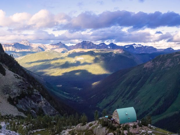 La photo a été prise à partir du refuge Conrad Kain et montre la vallée luxuriante jusqu’aux sommets glaciaires dénudés situés de l’autre côté. Les nuages orageux projettent de l’ombre sur le versant ensoleillé de la vallée.