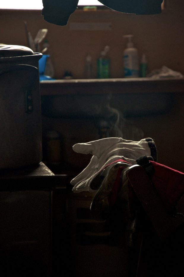 Une casserole est posée sur le comptoir près des gants placés au-dessus du linge sur une chaise. De la vapeur semble s’échapper des vêtements.