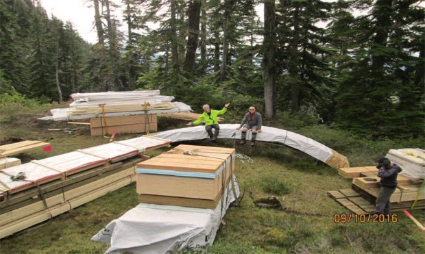 Chargement de bois et de fournitures de construction du refuge héliporté sur le chantier reculé. Se tenant sur ou près du chargement, les membres du club adoptent des positions différentes sur la photo.