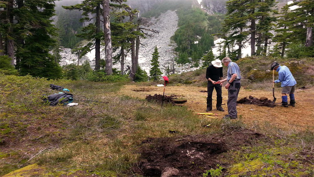 Deux membres de l’équipe semblant discuter de quelque chose à proximité de trous tout juste creusés pour la fondation du refuge.
