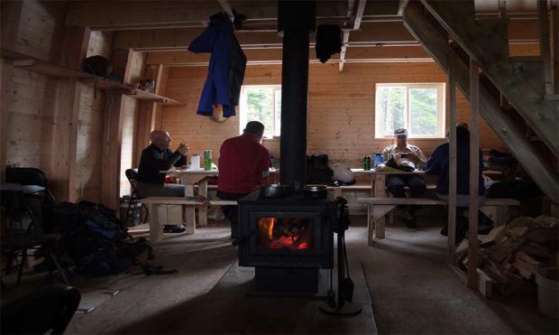Les flammes orange et les braises crépitent dans la poêle d’un noir foncé. Un groupe de bâtisseurs profite de leur pause autour d’une longue table.