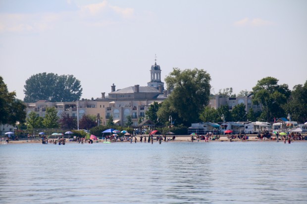 Une photo en couleurs prise à partir du large montrant la plage avec des baigneurs et des parasols de toutes les couleurs. Il y a des campeurs à droite, et la coupole du Victoria Hall en arrière-plan.