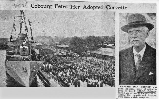 Un article de journal avec deux photos en noir et blanc; une photo du capitaine Dan Rooney, l’autre d’un navire de guerre amarré au port. L’équipage du navire est aligné sur le quai et il y a une grande foule derrière eux.