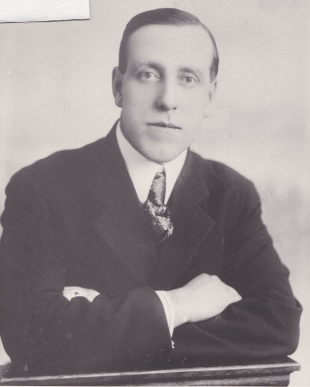 Sur cette photo, W.H. Bunting a les bras croisés. Il a l'air sérieux et il porte un costume sombre, une chemise claire et une cravate.