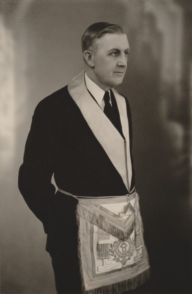 Charles McLeod est habillé en tenue de cérémonie maçonnique. Il porte un costume sombre et la photo a été prise de lui regardant à gauche.
