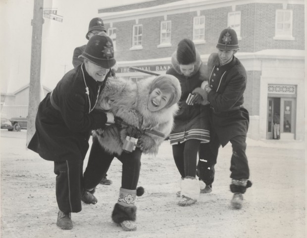 Keystone Kops arrêtant deux  participantes du concours de la reine des fourrures dehors devant une banque