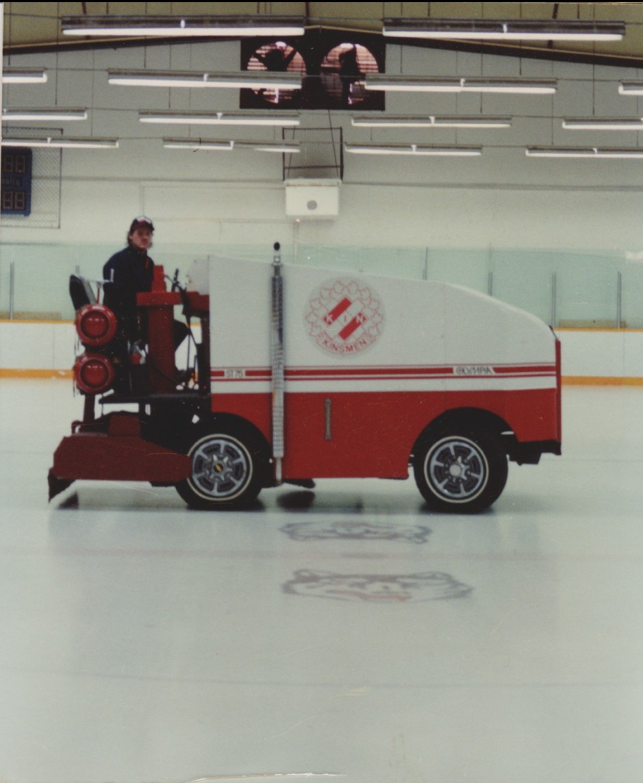 Un homme conduisant une surfaceuse sur une patinoire intérieure.