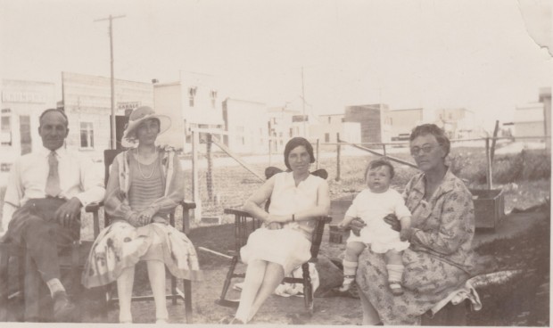 Charlie Krempeaux et sa famille assis dehors dans la rue principale de Le Pas, probablement pendant les mois les plus chauds d’été.