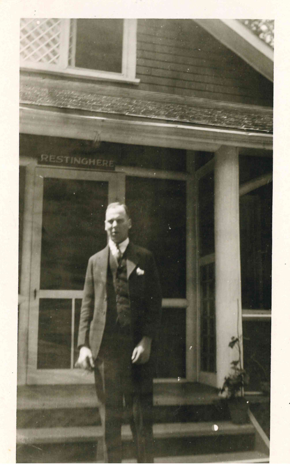 Photo d’une personne devant le chalet de la famille Lougheed à Banff (avec le nom du chalet, « Restinghere » au-dessus de la porte)