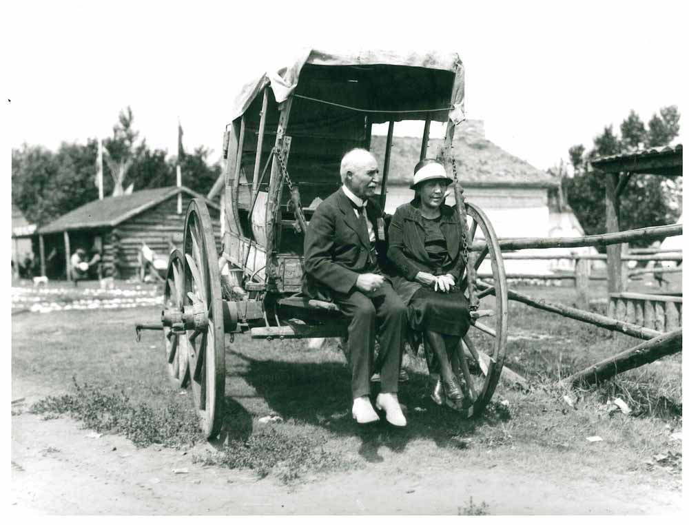 Belle et J.J. McHugh assis en arrière d’un vieux chariot couvert au Stampede, en 1925