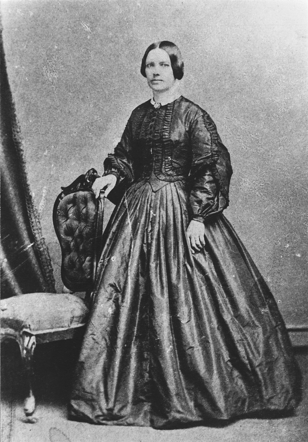 Photo de Lady Strathcona (Isabella Sophia Hardisty) debout près d’une chaise, en tenue de soirée