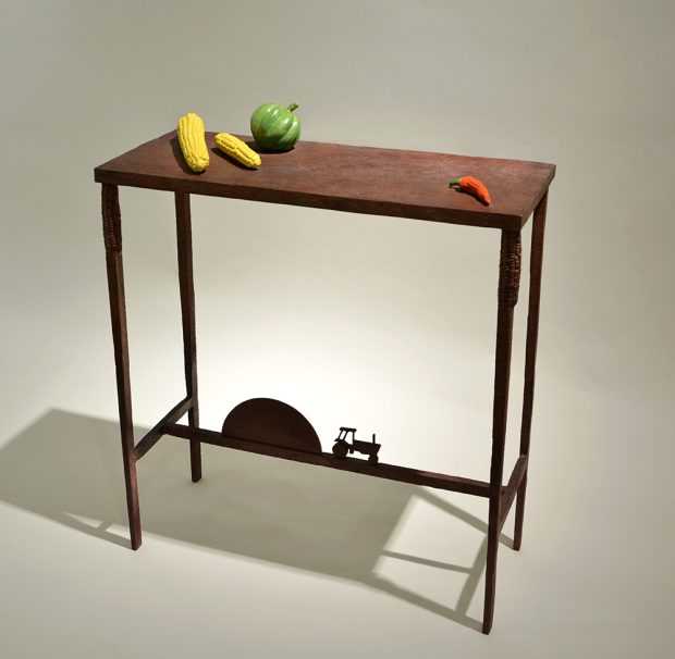 Table avec une silhouette de tracteur sur la structure du pied et des légumes sur la surface