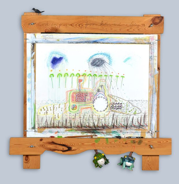 Dessin d'un fermier sur un tracteur, le cadre en bois comporte un oiseau, des crayons, et des grenouilles en céramique.