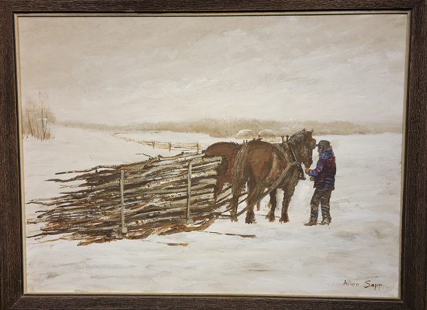 Une personne avec deux chevaux et un traîneau rempli de bûches de bois dans un champ enneigé.