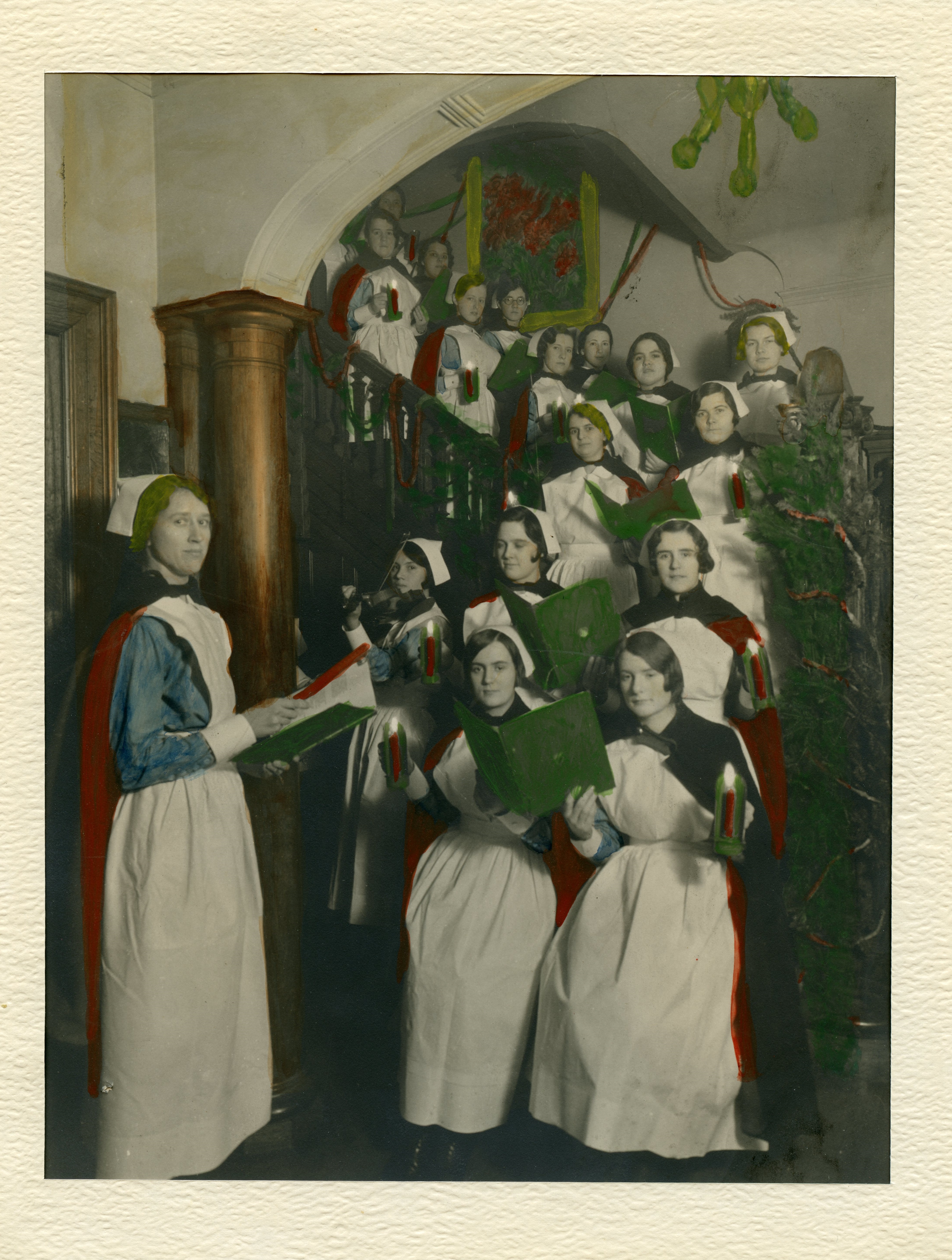 Des infirmières tenant bougies et recueils de cantiques s’alignent sur l’escalier dans une vieille photo. Une infirmière les dirige pendant qu’une autre joue du violon.