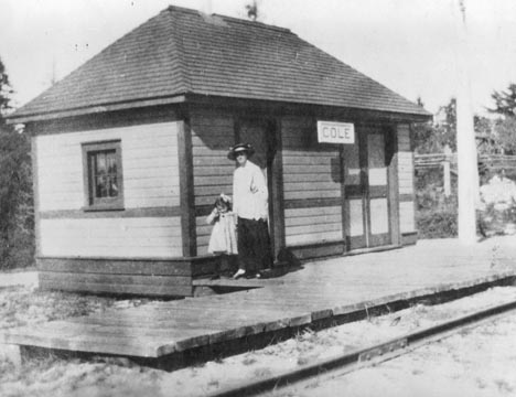 Une femme et un enfant devant la gare de Cole 