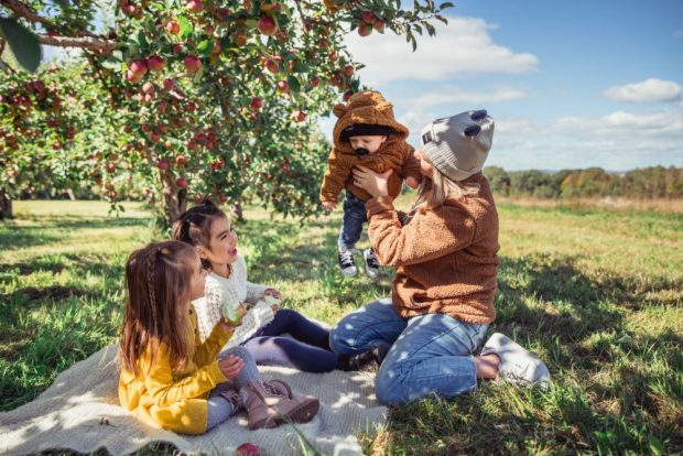 Une mère et trois enfants pique-niquent dans un verger