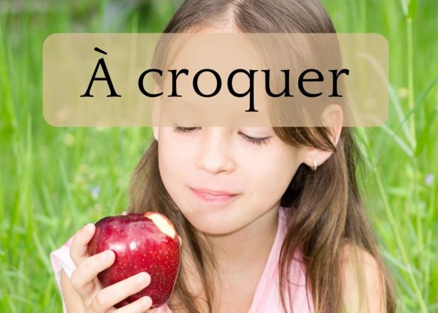 Une fillette regarde une pomme qu'elle a croquée