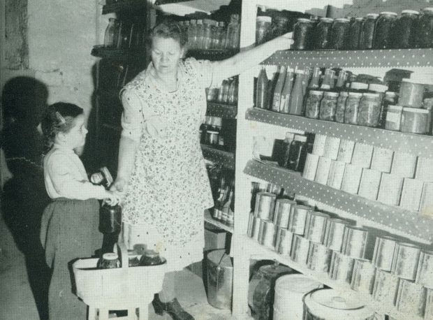 Une femme et une fillette rangent des conserves dans une chambre froide