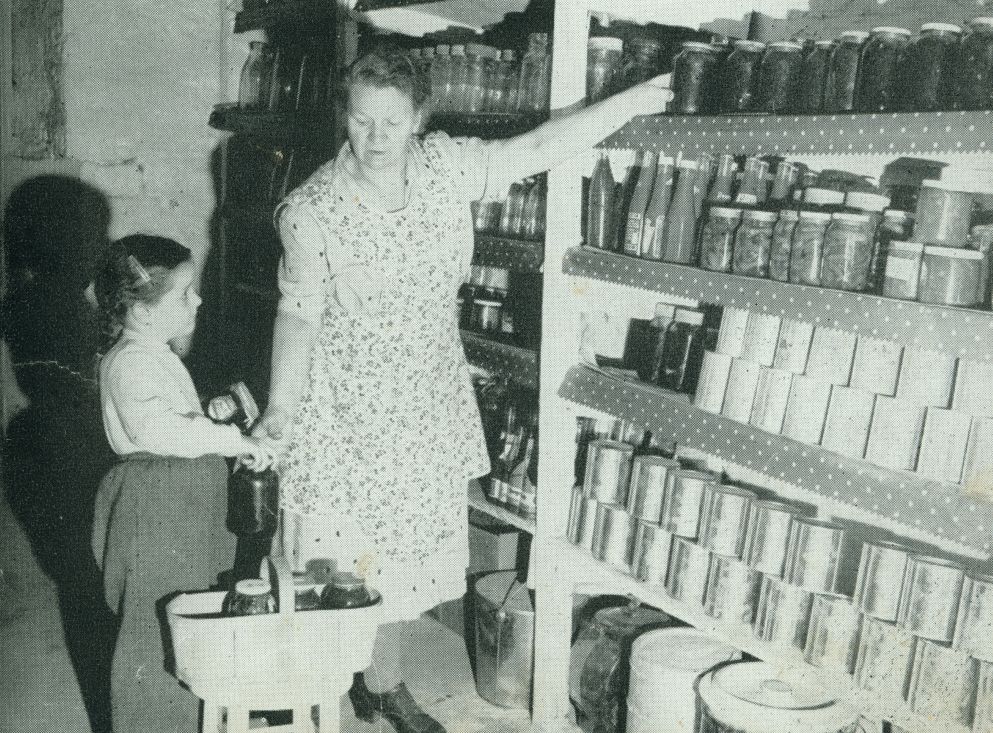 Une femme et une fillette rangent des conserves dans une chambre froide