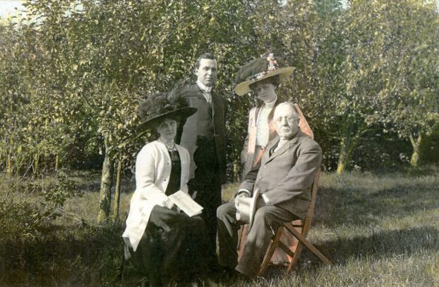 Photo de famille (père, mère, fils et fille) devant des arbres