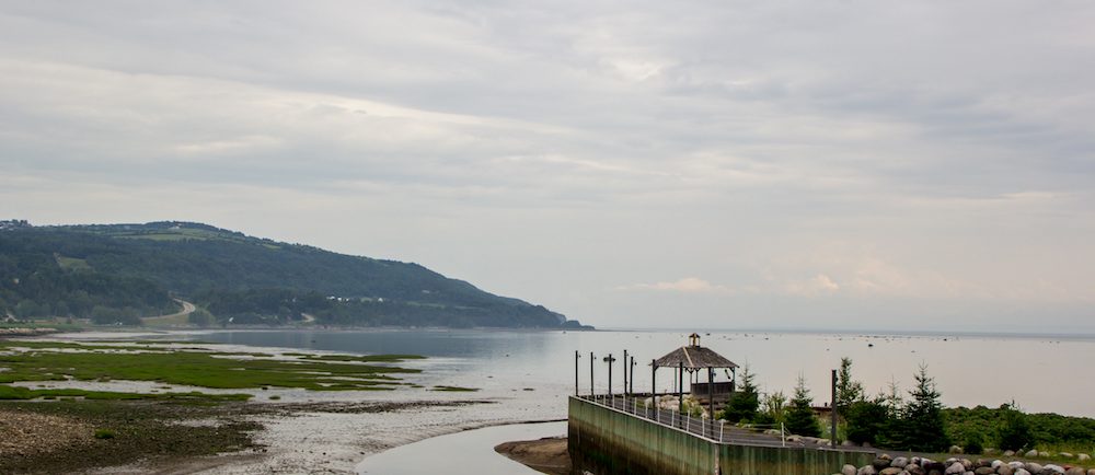 Vue sur la baie de Saint-Joseph-de-la-Rive à partir du site du Musée maritime de Charlevoix. Un quai de bois s'avance dans le fleuve au premier plan.