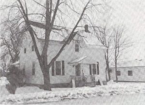 Photographie en noir et blanc d'une petite maison blanche de deux étages en hiver au 235, rue Ottawa, à Almonte.