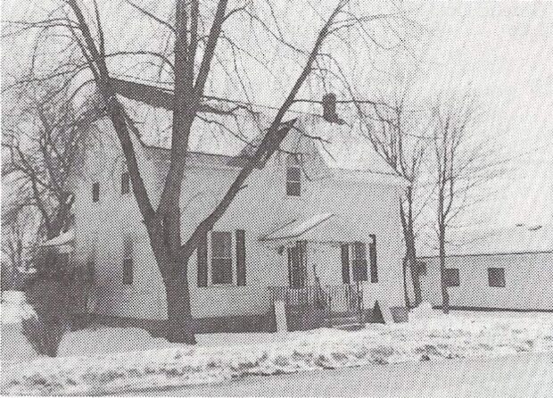 Photographie en noir et blanc d'une petite maison blanche de deux étages en hiver au 235, rue Ottawa, à Almonte.