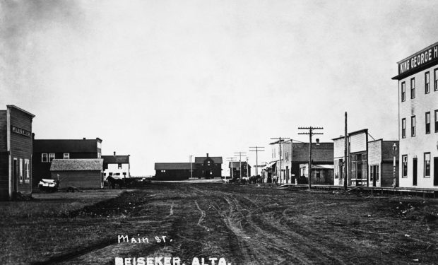 Rue Main, Beiseker : Cette large route de terre est parsemée de commerces de part et d’autre, et des chevaux et chariots sont attachés dehors. Du côté droit se dressent l’hôtel King George et des poteaux de téléphone. Cette rue mène à la gare de chemin de fer.