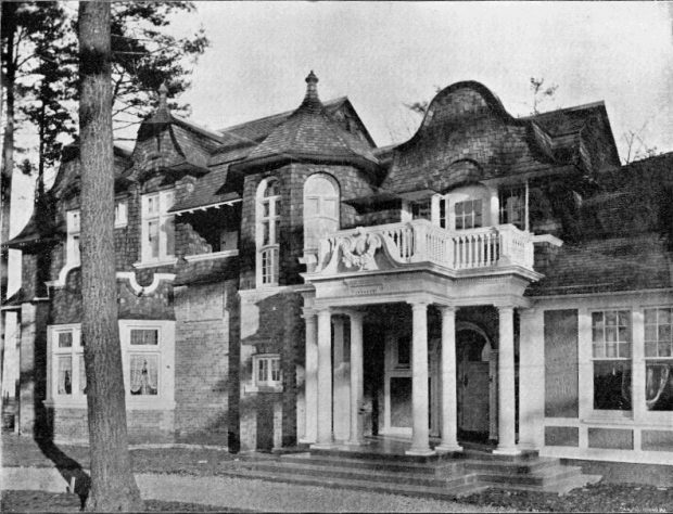 Image en noir et blanc d'une maison victorienne avec un grand balcon.