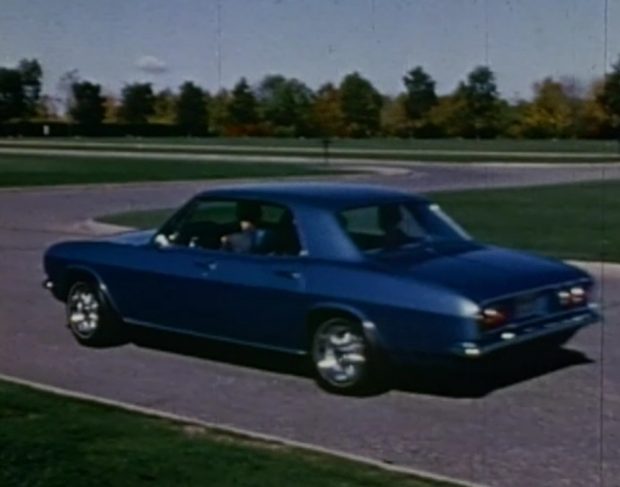 Une voiture de sport des années 1960 sur une piste d'essai sinueuse.