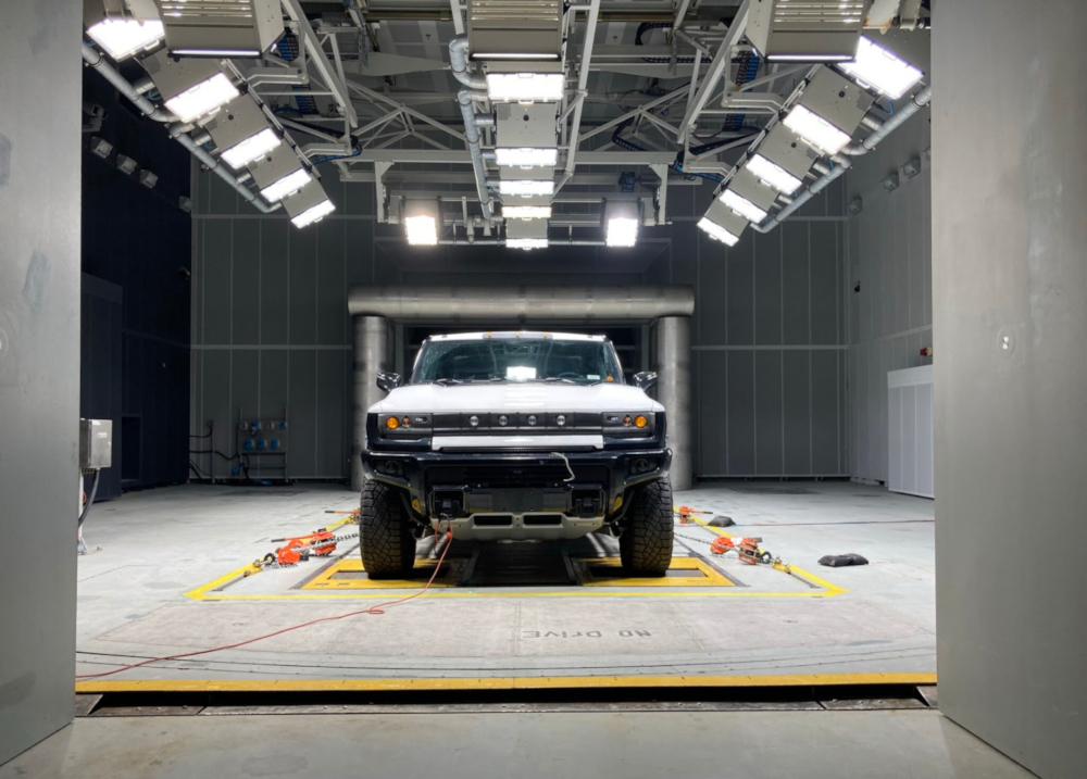Photo couleur d'un grand camion branché sur une prise murale. Le camion est monté sur un banc d'essai au milieu d'une grande salle industrielle.