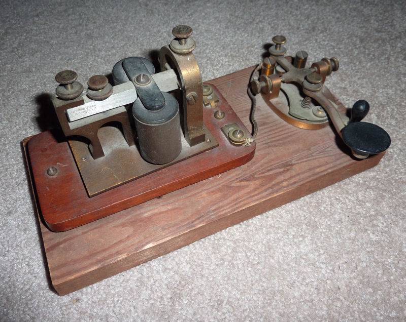 Manipulateur télégraphique et récepteur montés sur une plateforme en bois.