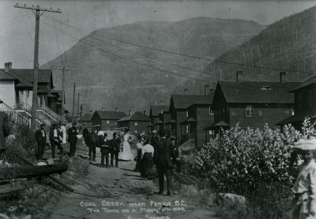 Hommes et femmes marchant le long d'une rue. Maisons à côtés en bois sont des deux côtés.