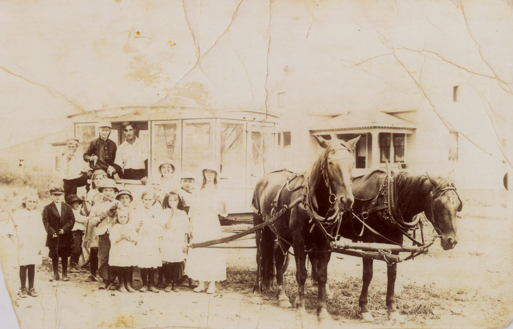 Wagon à crème glacée tiré par deux chevaux avec des enfants devant.