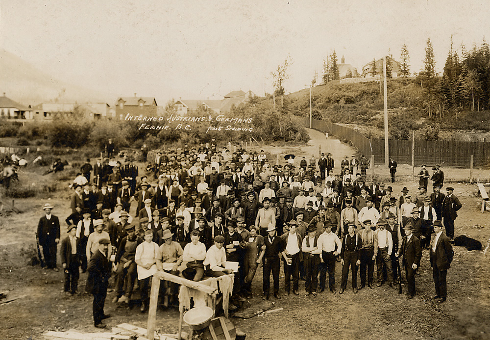 Grand groupe d'hommes debout dans une cour de camp.