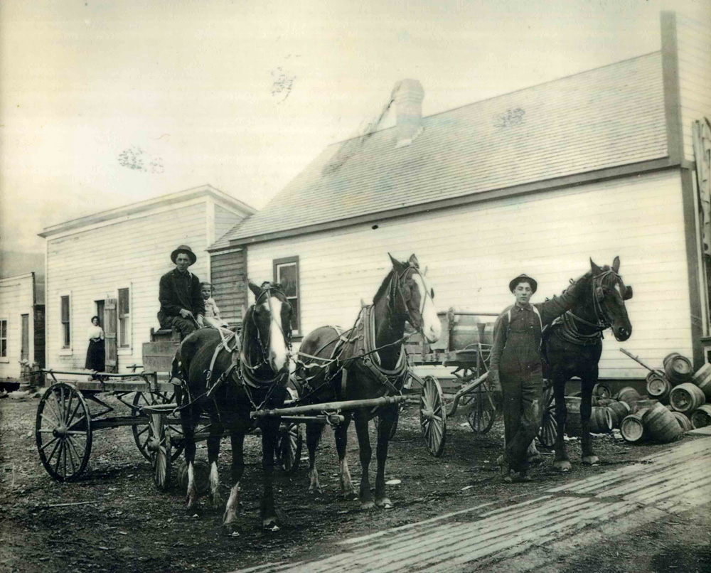  Un magasin en arrière-plan avec un wagon avec des chevaux à l'avant.
