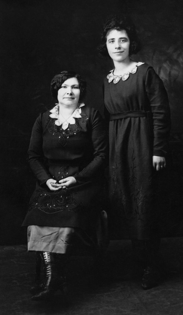 Une jeune femme debout à côté d'une femme plus âgée assise.