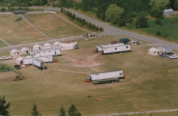 Vue aérienne de remorques, tentes et une piste d'atterrissage dans un champ.