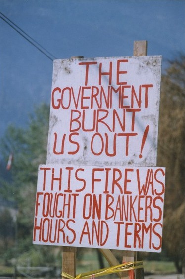 Une affiche de protestation faite à la main peinturée blanche avec lettres en rouge. 