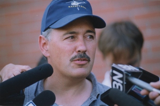 Homme coiffé d'une casquette parle dans quatre microphones.