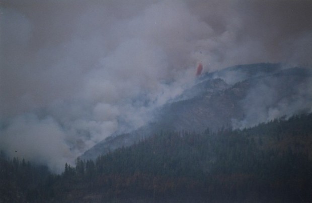 Feu et fumée dans les collines. Retardant rouge largué d'un hélicoptère. 