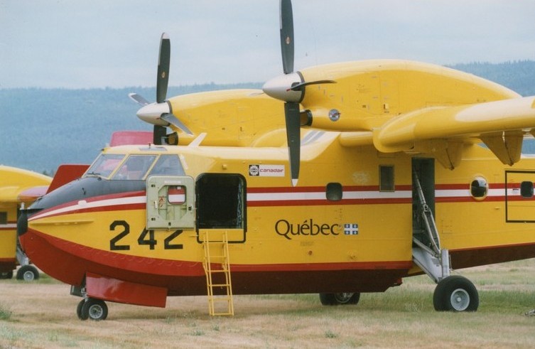 Avion jaune avec rayures rouges et blanches, doubles propulseurs, numéro 242 et Québec inscrits sur le fuselage.