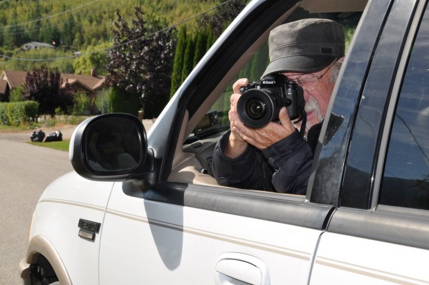 Un photographe prenant une photo assis dans son véhicule.