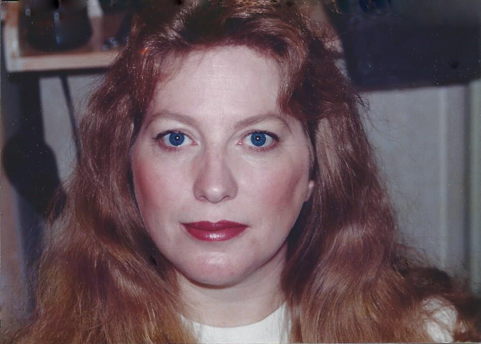 Portrait d'une femme à l'air sérieux aux cheveux roux et aux yeux bleus.