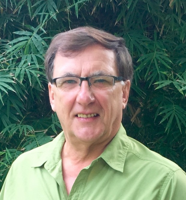 Photo d'un homme aux cheveux foncés avec lunettes, souriant.